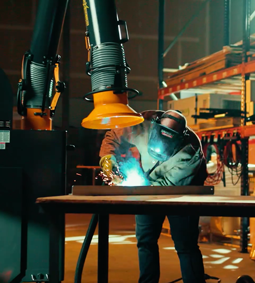 A welder working on a project while a Fume Xtractors portable unit works to extract welding fume and smoke.