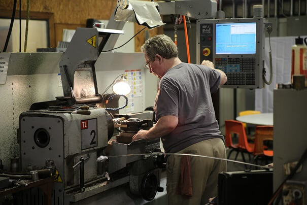 Machine operator working on a project at SCCM while a Blue Ox air cleaner cleans the air above him.