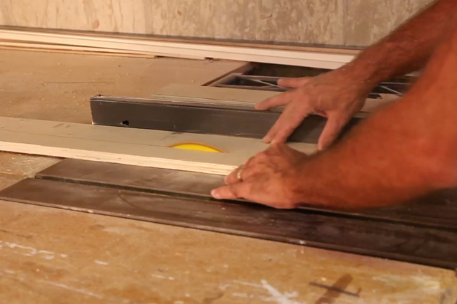 The hands of a machine operator working on a cutting wood project.