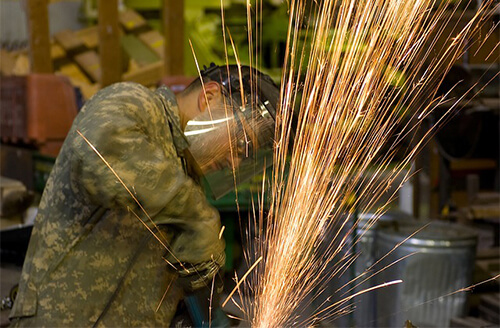 A machine operated grinding a work piece while sparks are produced.