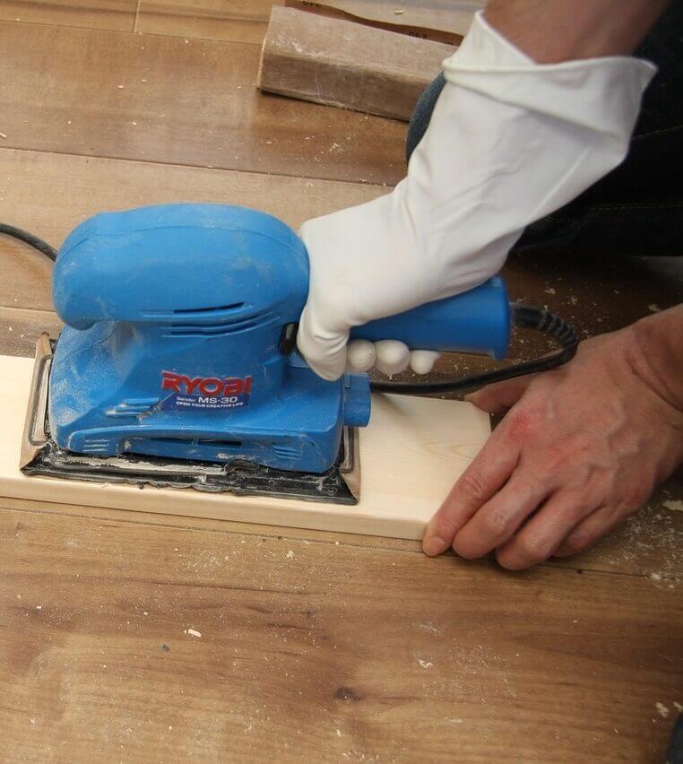 A panel of wood being sanded.