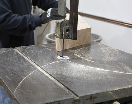 Machine operator cutting and shaping a wood workpiece.